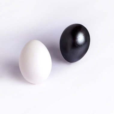 Beyaz arka planda siyah yumurta ve beyaz tavuk yumurtası. Birlik ve karşıtlık kavramı