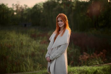 Bir kız baharda yeşil bir ormanda duruyor.