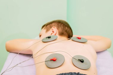 Fizyoterapi yardımıyla bir çocukta omurga eğriliği düzeltmesi. Myostimülasyon.