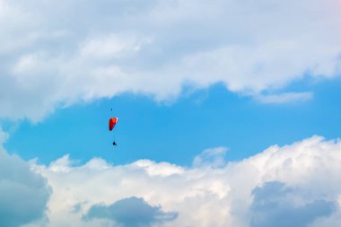 Bulutların arasında uçuyor. Adam yamaç paraşütü yapıyor ve kuş onun üzerinden uçuyor..