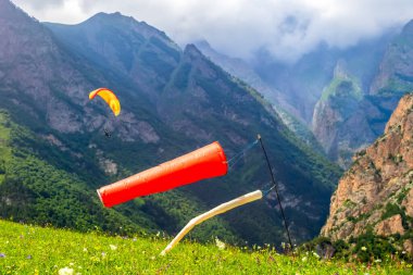 Dağ geçidinde bir paraglider üzerinde uçmak. Ön planda - rüzgarın yönünü belirlemek için rüzgar gülü.