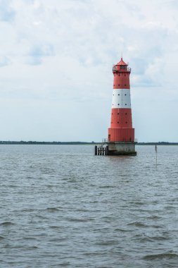 Arngast Deniz Feneri bulutlu bir gökyüzüne karşı suyun üzerinde duruyor, Wilhelmshaven, Jade Bight, Aşağı Saksonya, Almanya