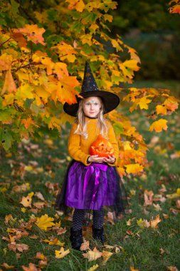 5 yaşında cadı gibi giyinmiş balkabağı, çocuk sevinci, Cadılar Bayramı kostümleri, gizemli ruh hali.