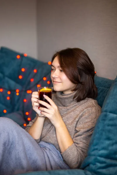 Kısa saçlı güzel esmer, huş ağacından bir koltukta oturur ve içer. Sıcak şarap, feminizm, rahatlama, karanlık oda, izolasyon, alkol, geleneksel içkiler, akşam rahatlaması, yalnızlık... 