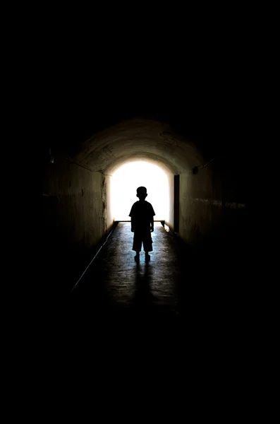 年轻的男孩，在长长的隧道走道 图库图片