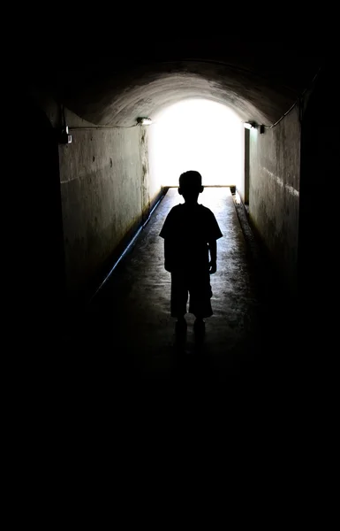 Young boy in long tunnel walkway — Stock Photo, Image