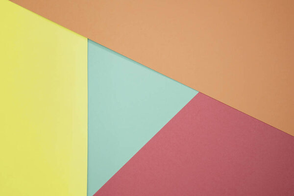 Абстрактный фон из цветной бумаги красного, желтого и зеленого цветов. Минимальные геометрические формы и линии в пастельных цветах. Цветная пастельная бумага текстура минимализм. Картонные фоны.
