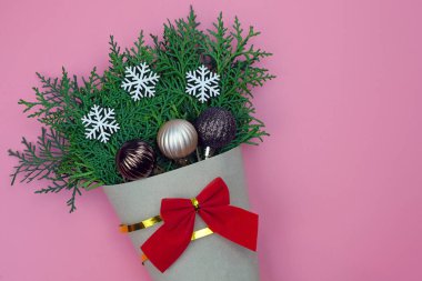 Bir buket çalı çırpı kağıdının üstüne sarılmış. Yeni yıl temalı ve mesaj için bir yer. Noel kar taneleri, pembe arka planda noel baloları. minimalist tasarım, kopyalama alanı.