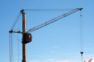 Gökyüzünün arka planında paslı bir vinç var. Şehrin kenar mahallelerinde terk edilmiş eski tarz vinçler..  