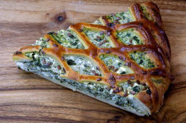 Tahtada peynirli ve ıspanaklı turta. Susam tohumları serpiştirilmiş bir dilim ıspanaklı turta. Lezzetli ev yapımı lezzetli hamur işleri.. 