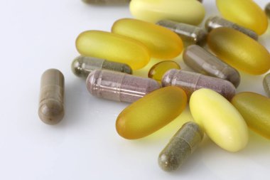Beyaz arka planda bir sürü farklı hap var. Gıda takviyesi Omega 3, D vitamini, magnezyum. Farklı boyutlarda ve yakın plan renklerde kapsüller. 