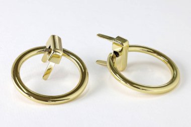 Çanta için metal halka. Kaygan altın tepeciği. Çantanın sapını beyaz arka plana takmak için yüzükler. Altın rengi çanta aksesuarları.. 