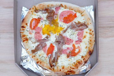 Pizza teslimatı. Yumurtalı, jambonlu ve salamlı pizza. Etli pizza, domates ve ince kenarlı peynir. Karton kutuda nefis fast food.