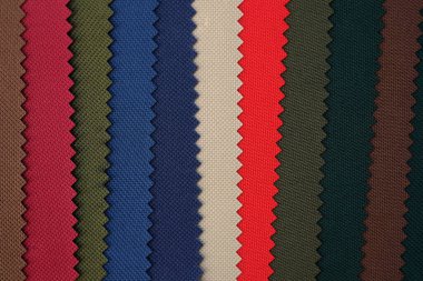 Dikiş torbaları ve sırt çantaları için renkli kumaş örnekleri. Polyester mavi, yeşil, bej ve kırmızı kumaş. Farklı tonlarda yoğun kumaş örnekleri paleti. 