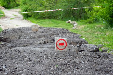 Yol boyunca yol bir yol tabelası ile kapatıldı. Kırmızı boyalı tuğla ve geçiş yasağı. Köydeki yolun tamiri. Asfaltsız yol.
