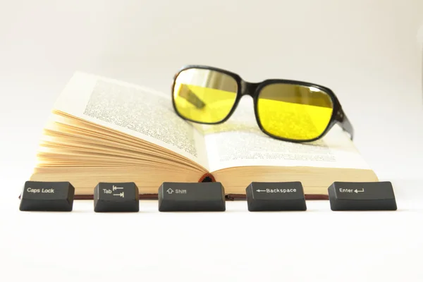 Un libro abierto, llaves de computadora y gafas de sol — Foto de Stock