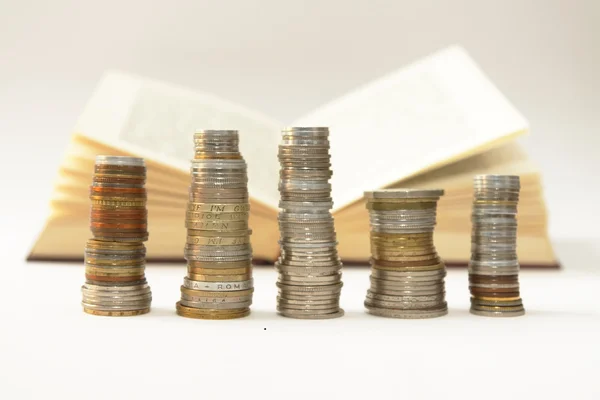 Stakes of coins an an open book — Stock Photo, Image