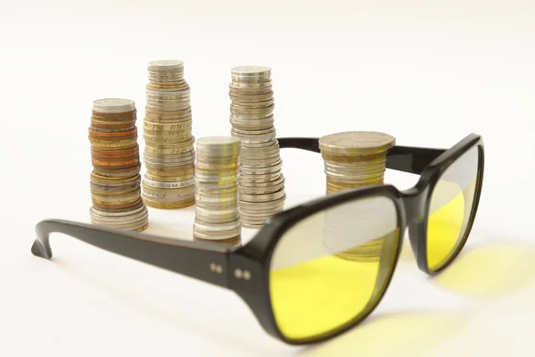 Stakes of coins and old style sunglasses — Stock Photo, Image