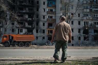 Bir adam Ukrayna 'daki askeri operasyonlardan kalma bir bombayla vurulan yıkılmış bir evin yanında duruyor.