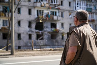 Bir adam Ukrayna 'daki askeri operasyonlardan kalma bir bombayla vurulan yıkılmış bir evin yanında duruyor.