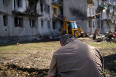 Bir adam Ukarin 'deki askeri operasyonlar sırasında yıkılmış bir evin önünde duruyor.