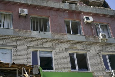 Ukrayna 'daki savaşta patlayan bir bombadan dolayı kırık camlı binanın ön cephesi. Kırık camlarda rüzgarda sallanan perdeler