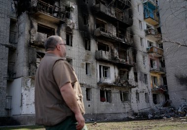 Bir adam Ukarin 'deki askeri operasyonlar sırasında yıkılmış bir evin önünde duruyor.