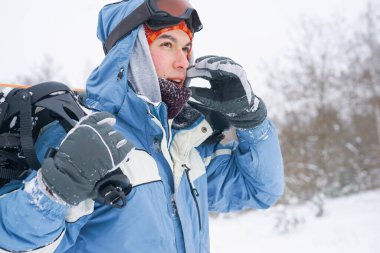 Kar yamacında bir snowboardcunun portresi. Kar kaykaylı, şapkalı ve dağ maskeli Freerider.