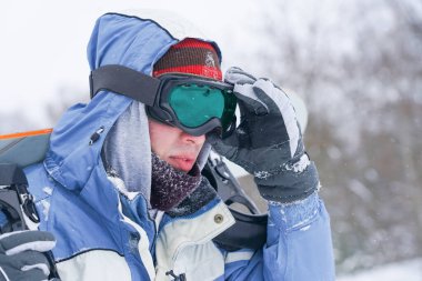 Kar yamacında bir snowboardcunun portresi. Kar kaykaylı, şapkalı ve dağ maskeli Freerider.