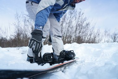 Adam kaykayı kayağa bağlıyor.