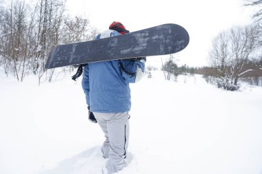 Freerider kar tozunun içinden geçiyor. Elinde bir snowboard tutuyor.