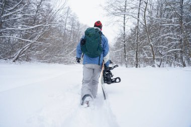 Freerider kar tozunun içinden geçiyor. Elinde bir snowboard tutuyor.