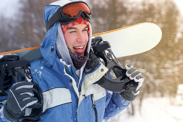 Kar yamacında bir snowboardcunun portresi. Kar kaykaylı, şapkalı ve dağ maskeli Freerider.