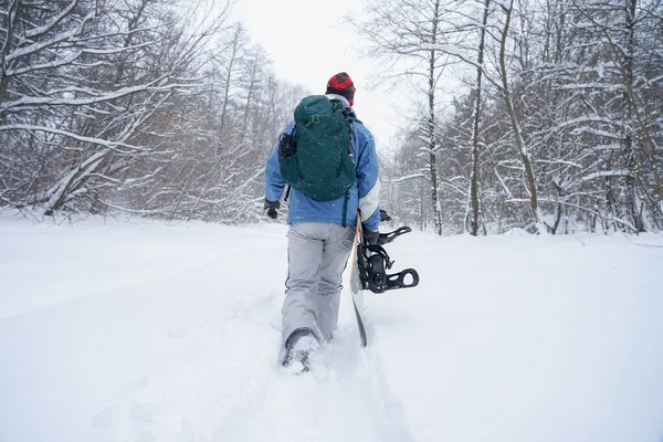 Freerider kar tozunun içinden geçiyor. Elinde bir snowboard tutuyor.