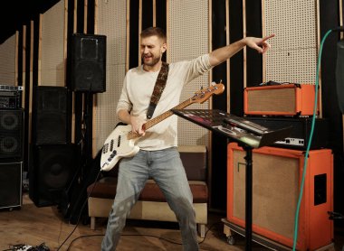 Adam bas gitar çalıyor. Bas gitarist elinde bir elektro gitar tutuyor ve onunla çalıyor.