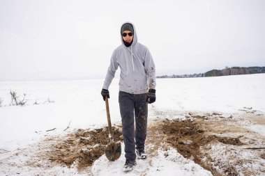 Karda çukur kazdıktan sonra çamura düşen adam. Pantolon ve giysiler kirlenmiş.