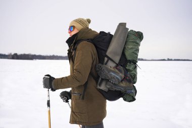 Kış yürüyüşü sırasında polarize gözlüklü bir adamın portresi.