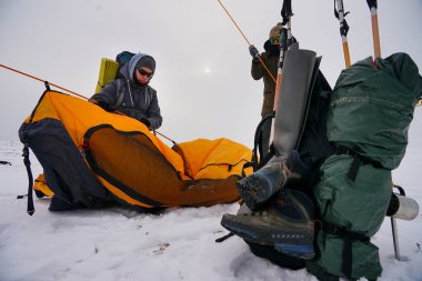 İki adam karda bir çadır kuruyor. Kış seferi sırasında aşırı koşullarda bir çadır kurmak. Kış yürüyüşü