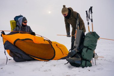 İki adam karda bir çadır kuruyor. Kış seferi sırasında aşırı koşullarda bir çadır kurmak. Kış yürüyüşü