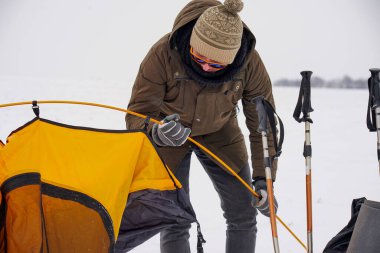 İki adam karda bir çadır kuruyor. Kış seferi sırasında aşırı koşullarda bir çadır kurmak. Kış yürüyüşü