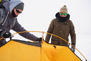 İki adam karda bir çadır kuruyor. Kış seferi sırasında aşırı koşullarda bir çadır kurmak. Kış yürüyüşü