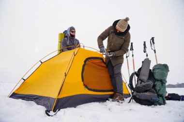 İki adam karda bir çadır kuruyor. Kış seferi sırasında aşırı koşullarda bir çadır kurmak. Kış yürüyüşü