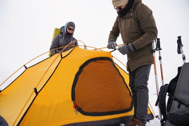 İki adam karda bir çadır kuruyor. Kış seferi sırasında aşırı koşullarda bir çadır kurmak. Kış yürüyüşü