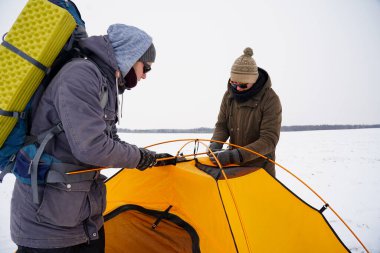 İki adam karda bir çadır kuruyor. Kış seferi sırasında aşırı koşullarda bir çadır kurmak. Kış yürüyüşü