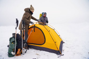 İki adam karda bir çadır kuruyor. Kış seferi sırasında aşırı koşullarda bir çadır kurmak. Kış yürüyüşü