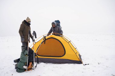 İki adam karda bir çadır kuruyor. Kış seferi sırasında aşırı koşullarda bir çadır kurmak. Kış yürüyüşü