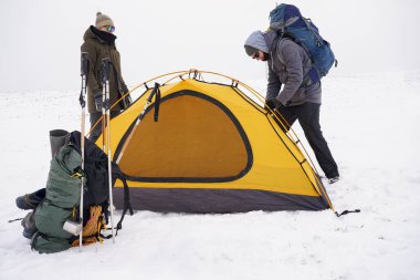 İki adam karda bir çadır kuruyor. Kış seferi sırasında aşırı koşullarda bir çadır kurmak. Kış yürüyüşü