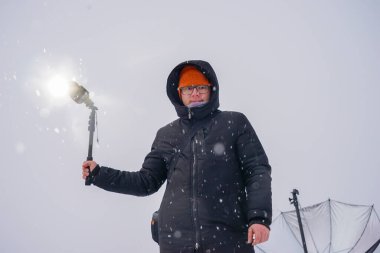 Açık hava fotoğrafçısı elinde bir stüdyo flaşı tutuyor. Doğada çekim.