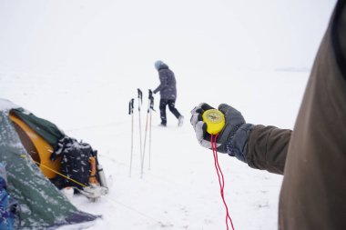 Elinde kocaman sarı bir pusula var. Bir gezgin kışın kuzey kutbunda eldivenli bir pusula tutar. Kış gezisinde pusula