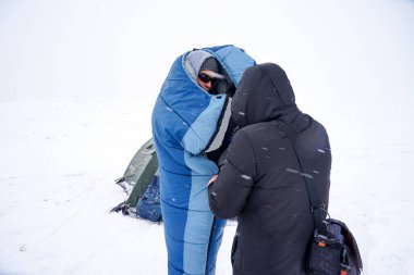 Portrait of a guy in a sleeping bag during the winter expedition.	